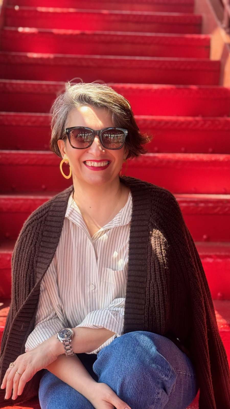 Natalia sitting on vibrant red stairs near Azabudai Hills, golden hour sunlight